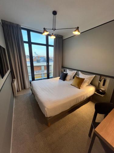 a bedroom with a large bed and a large window at L'Échappée - Hôtel Casino Dieppe in Dieppe