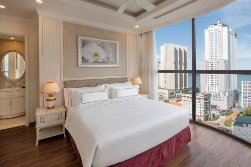 a bedroom with a large white bed and a large window at Meliá Vinpearl Nha Trang Empire in Nha Trang