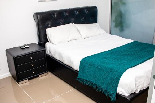 a bed with a black headboard next to a night stand at Urban Oasis Apartments at Freedom Plaza in Windhoek