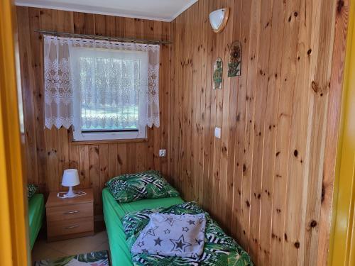 ein Schlafzimmer mit einem grünen Bett an einer Holzwand in der Unterkunft Domek letniskowy nad jeziorem w Gołdapi, Wczasowa72 in Goldap