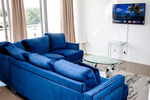 a blue couch in a living room with a table at Urban Oasis Apartments at Freedom Plaza in Windhoek