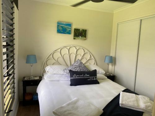 a bedroom with a white bed with pillows on it at Haven Guesthouse in Holloways Beach
