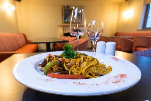 a plate of spaghetti on a table with wine glasses at Castle Varagh Hotel & Bar in Westmeath