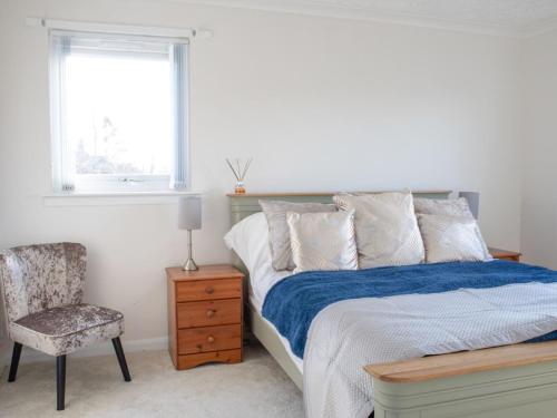 a bedroom with a bed and a chair and a window at Villa Solas by Interhome in Kensaleyre