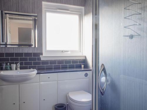 a bathroom with a toilet and a sink and a window at Villa Solas by Interhome in Kensaleyre