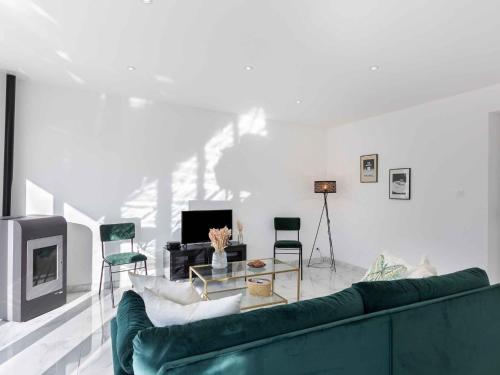 ein Wohnzimmer mit einem grünen Sofa und einem TV in der Unterkunft Holiday Home La cinquième Saison by Interhome in Plouescat