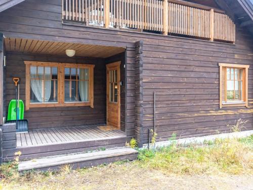 une maison en bois avec une valise verte sur la terrasse couverte dans l'établissement Holiday Home Saukonpiilo 2 by Interhome, à Pyhätunturi