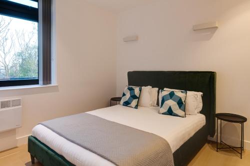 a bedroom with a bed with blue and white pillows at Charles Hope London Brentford in Brentford