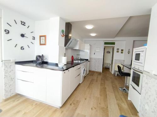 een keuken met witte kasten en een klok aan de muur bij Apartment Suecia by Interhome in Benidorm