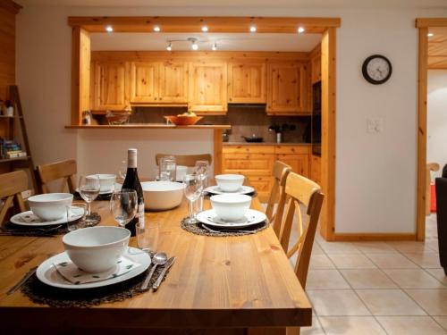 - une cuisine avec une table en bois, des assiettes et des verres à vin dans l'établissement Apartment Ambre 1 by Interhome, à Villars-sur-Ollon