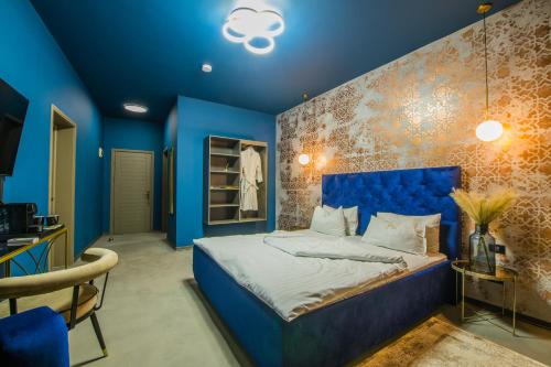 a blue bedroom with a bed and a blue wall at Pensiunea Casa Buna in Gîrbova