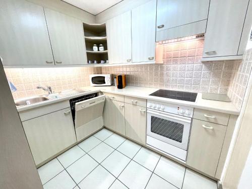 - une cuisine blanche avec des placards blancs et un évier dans l'établissement Apartment Blumenweg 4-412 by Interhome, à Engelberg