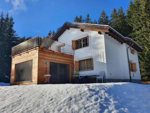 a house in the snow in front of trees at Apartment Lieptgas by Interhome in Lenzerheide