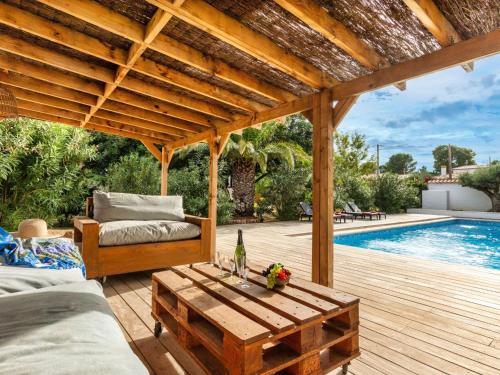 a wooden pergola with a table next to a pool at Villa Gaia by Interhome in Miami Platja