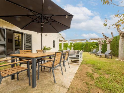 a patio with a wooden table and chairs and an umbrella at Holiday Home La Barca by Interhome in Cambrils