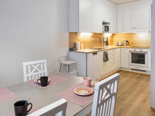 eine Küche mit weißen Schränken und einem Tisch und Stühlen in der Unterkunft Holiday Home Hovikatti by Interhome in Vuokatti