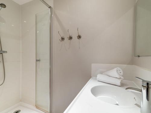 une salle de bain blanche avec une douche et un lavabo dans l'établissement Apartment Les Roches Rouges - Lavachet by Interhome, à Tignes