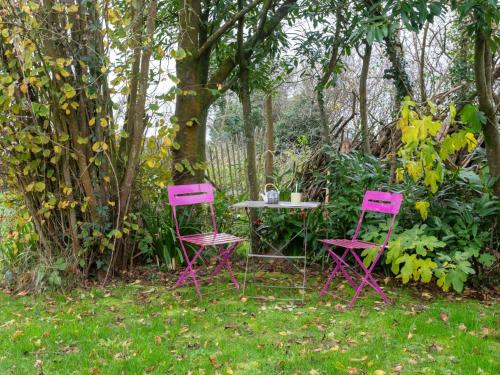deux chaises roses et une table sous un arbre dans l'établissement Holiday Home La Longére by Interhome, à Surville