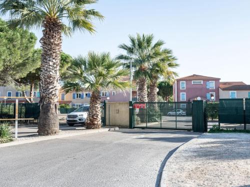 un parking avec des palmiers et une clôture dans l'établissement Apartment Village Marin Catalan by Interhome, à Torreilles