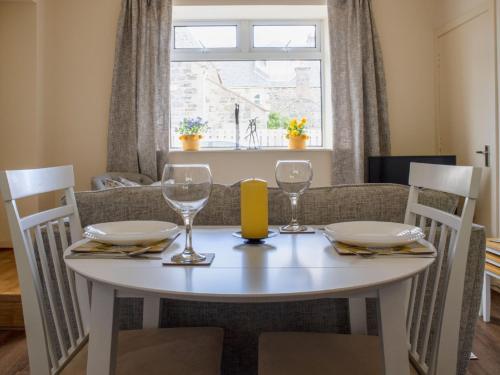 uma mesa de jantar com dois copos e uma janela em Apartment Flat 2 Keeper's Cottage by Interhome em Stenscholl