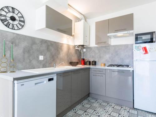kuchnia z białymi urządzeniami i zegarem na ścianie w obiekcie Apartment Coutant-2 by Interhome w mieście Royan