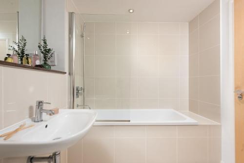 a white bathroom with a sink and a bath tub at 22 Zinc in Newquay
