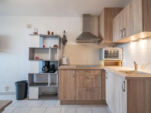 - une cuisine avec des placards en bois et un four micro-ondes dans l'établissement Studio Les Floralies II-12 by Interhome, au Grau-du-Roi