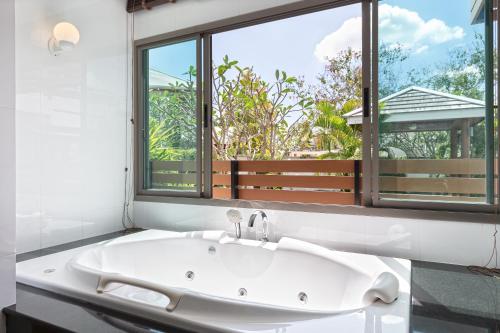a white bath tub in a bathroom with a window at Villa Piyada in Chalong 