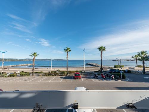 a view of a parking lot with palm trees and the ocean at Apartment Le Palazzo del Mar-12 by Interhome in Cavalaire-sur-Mer
