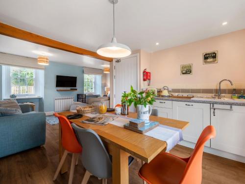 a kitchen and living room with a wooden table and chairs at Holiday Home Cherry Orchard House by Interhome in Mevagissey