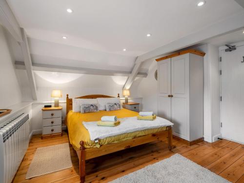 a bedroom with a bed with yellow sheets and wooden floors at Holiday Home Cherry Orchard House by Interhome in Mevagissey