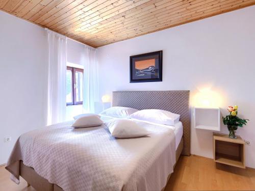 Schlafzimmer mit einem Bett mit weißer Bettwäsche und Kissen in der Unterkunft Holiday Home Casa Negri by Interhome in Labin