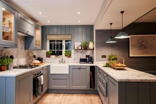 a kitchen with gray cabinets and white counter tops at ALTIDO Lathallan Mill Farmhouse in Fife