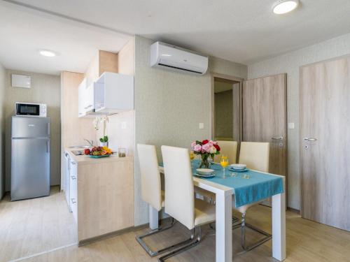 een keuken en een tafel in een kleine keuken met een tafel en stoelen bij Holiday Home Seaside mobile home by Interhome in Šilo