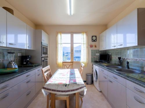 een keuken met witte kasten en een tafel met stoelen bij Apartment Le Néflier by Interhome in Pégomas