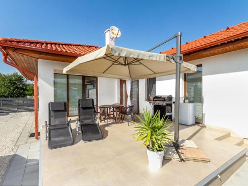 un patio con sombrilla, sillas y parrilla en Holiday Home Emily by Interhome, en Csisztapuszta