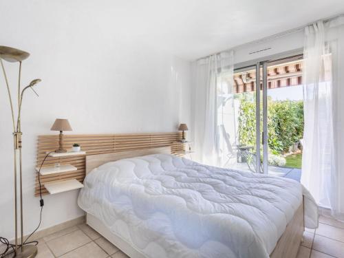 une chambre blanche avec un grand lit et une fenêtre dans l'établissement Apartment Le Marbeau-2 by Interhome, à Cagnes-sur-Mer