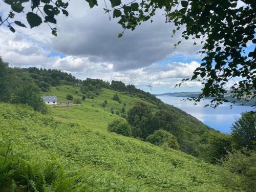 a green hill with a house on top of it at Holiday Home Peter's Shed by Interhome in Drumnadrochit