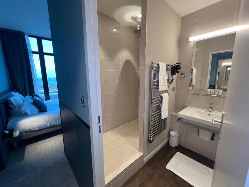 a bathroom with a shower and a sink and a bed at L'Échappée - Hôtel Casino Dieppe in Dieppe