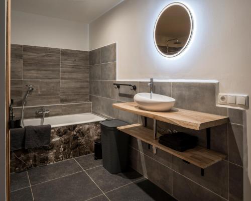 a bathroom with a sink and a tub and a mirror at In de 7e Hemel in Grashoek