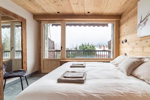 a bedroom with a large bed and a large window at Cocon au pied des pistes de ski du Mont-d'Arbois in Megève