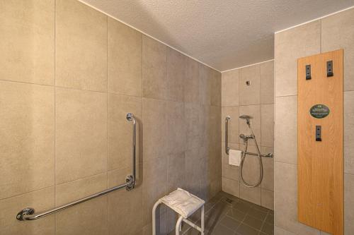 a bathroom with a shower with a toilet and a stool at B&B HOTEL Vannes Est Golfe du Morbihan in Vannes
