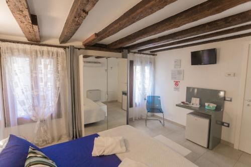 een slaapkamer met een blauw bed en een kamer met een tv bij B&B Antico Orologio in Chioggia