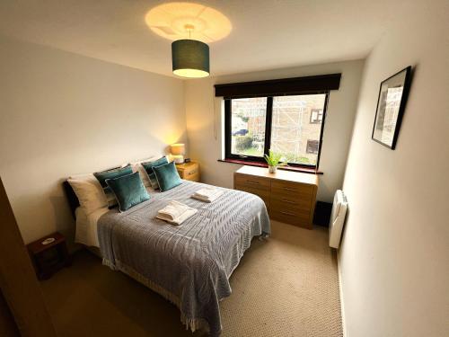ein Schlafzimmer mit einem Bett mit blauen Kissen und einem Fenster in der Unterkunft Brunswick Court in Cowes