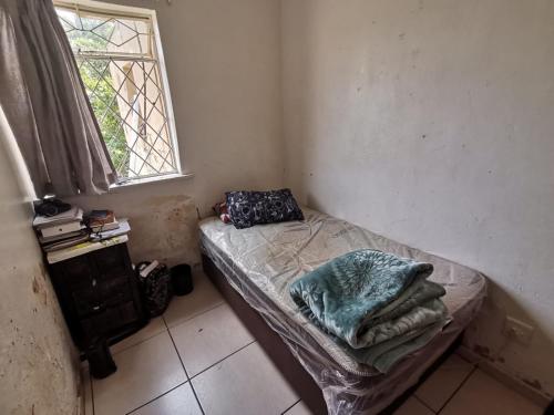 een klein bed in een kamer met een raam bij House n Car in Krugersdorp