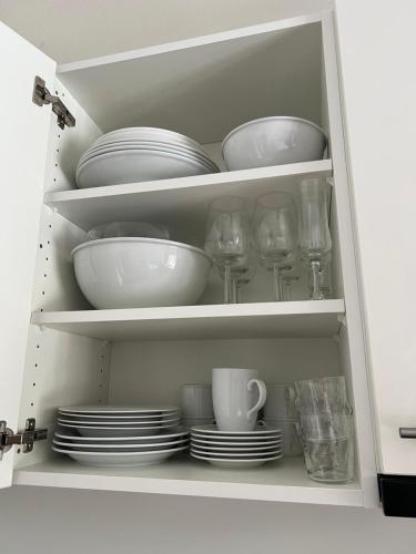 einem weißen Schrank mit Tellern, Tassen und Geschirr in der Unterkunft Studio Flims in Flims