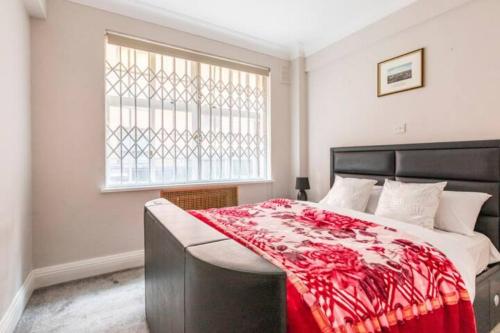 a bedroom with a bed with a red blanket on it at Great Mayfair London Flat in London