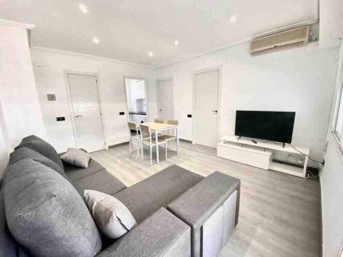 sala de estar con sofá y TV de pantalla plana en Apartamento en la playa Els Terrers, en Benicàssim