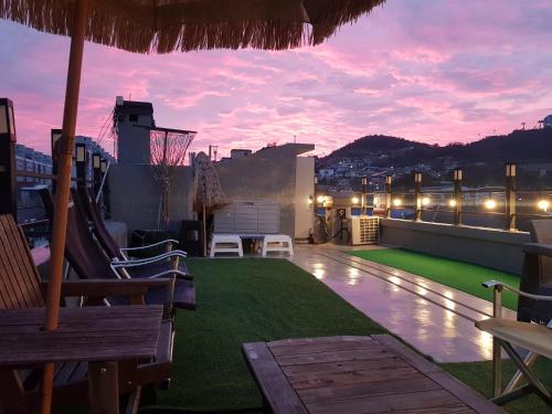 eine Dachterrasse mit Blick auf die Stadt bei Sonnenuntergang in der Unterkunft Leehakjang guesthouse in Mokpo