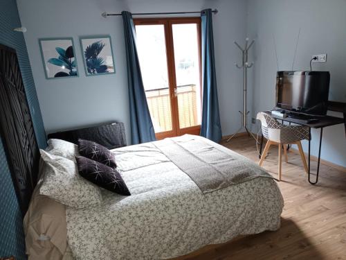 een slaapkamer met een bed, een televisie en een raam bij Au pied des montagnes. in Saint-Jean-de-Maurienne